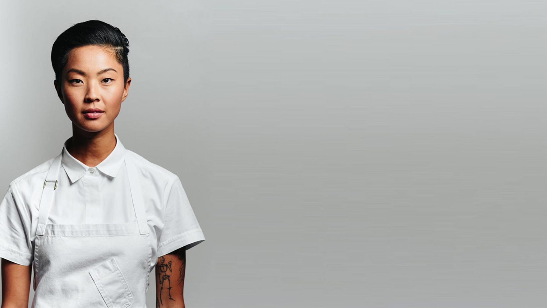 Kristen Kish a Korean chef facing the camera infront of a grey background