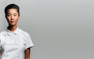 Kristen Kish a Korean chef facing the camera infront of a grey background