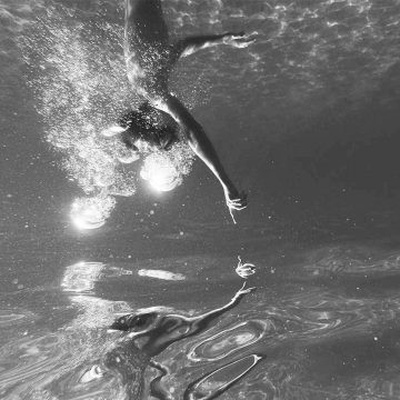 swimmer reaches to the bottom a pool blowing bubbles