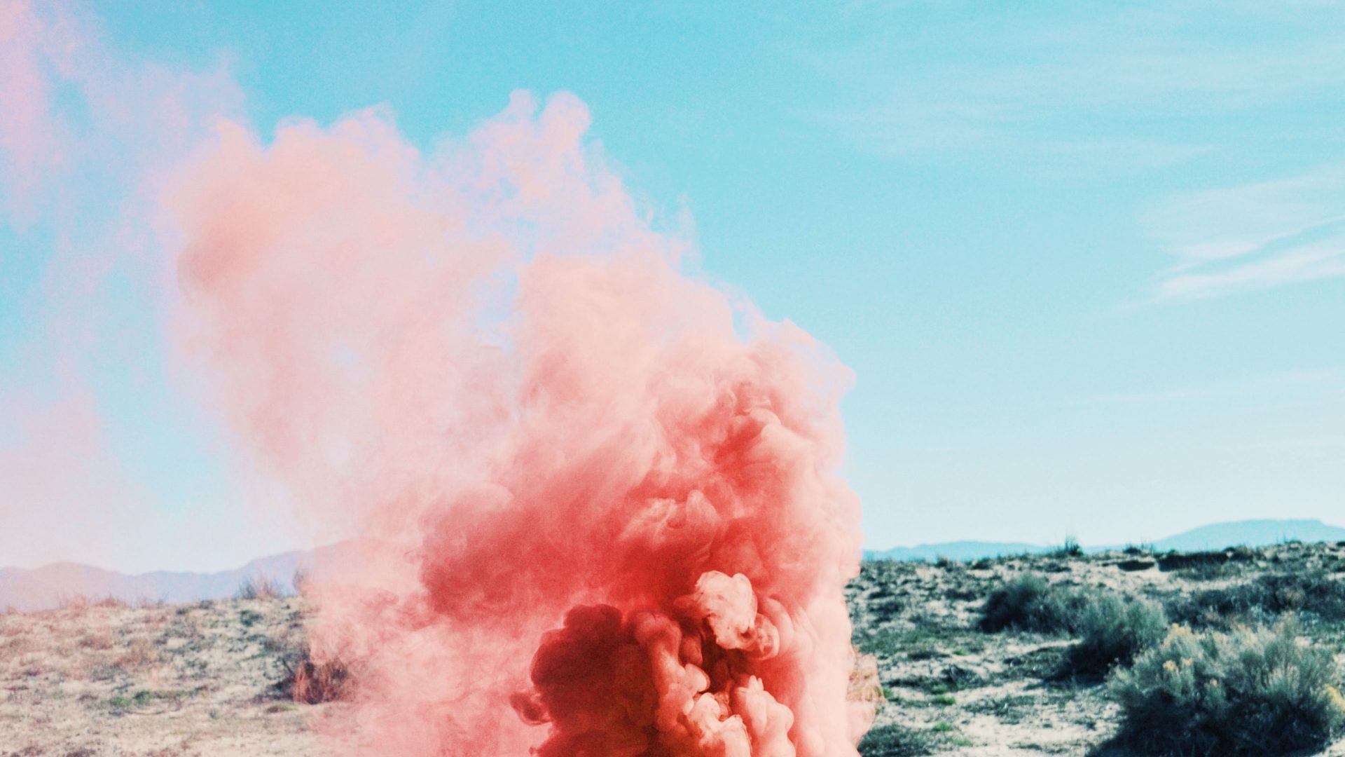 A cloud of pink smoke billows out of a suitcase