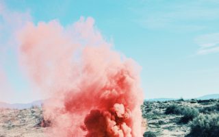 A cloud of pink smoke billows out of a suitcase