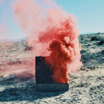 A cloud of pink smoke billows out of a suitcase