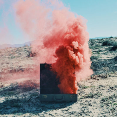A cloud of pink smoke billows out of a suitcase