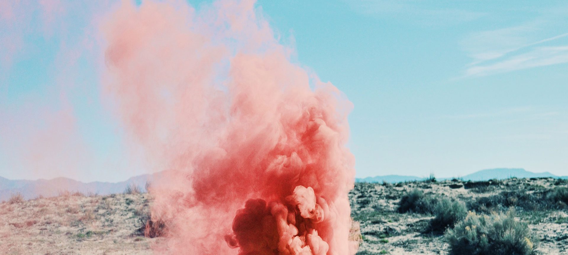 A cloud of pink smoke billows out of a suitcase