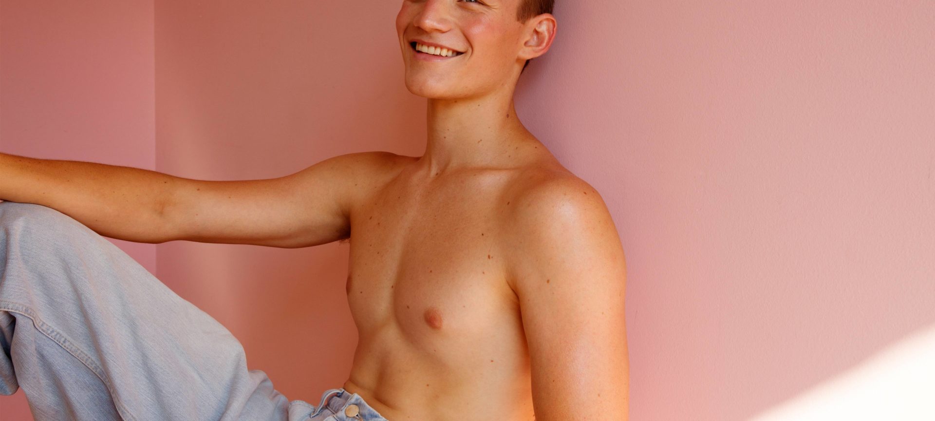 a black man infront of a nude background poses with a flower