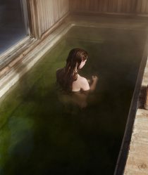 A red haired model sits in a green pool with her back turned