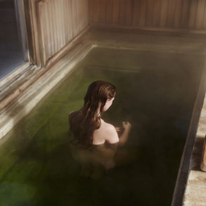 A red haired model sits in a green pool with her back turned