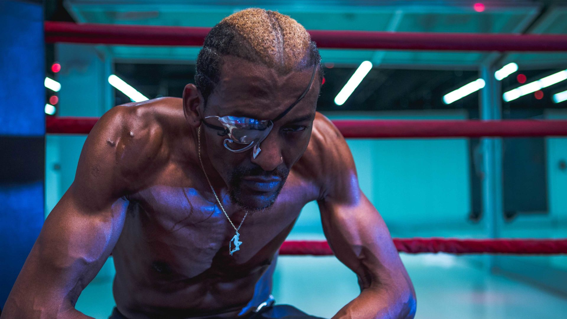 Michael Olijade sits infront of the ring in a dimly lit gym
