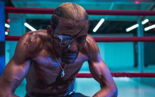 Michael Olijade sits infront of the ring in a dimly lit gym