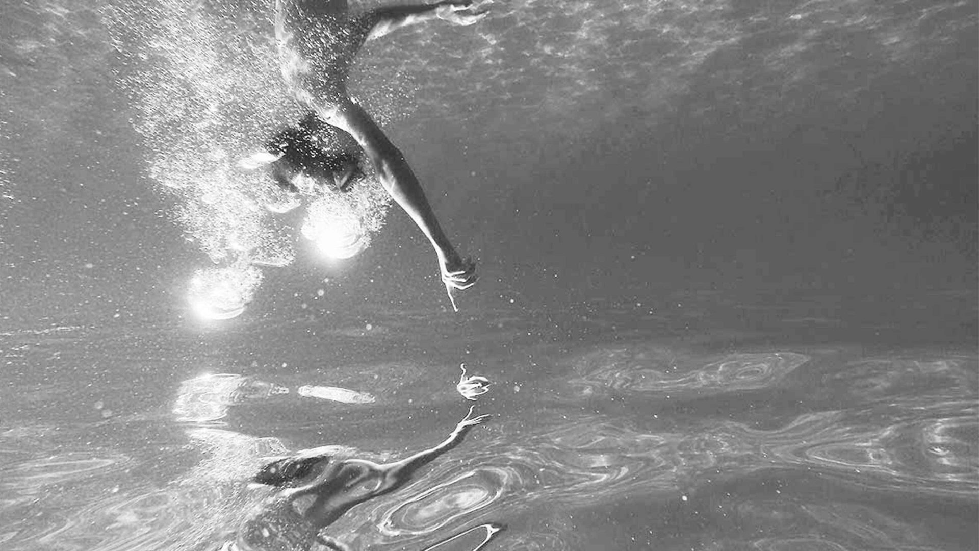 swimmer in a pool swims towards his reflection