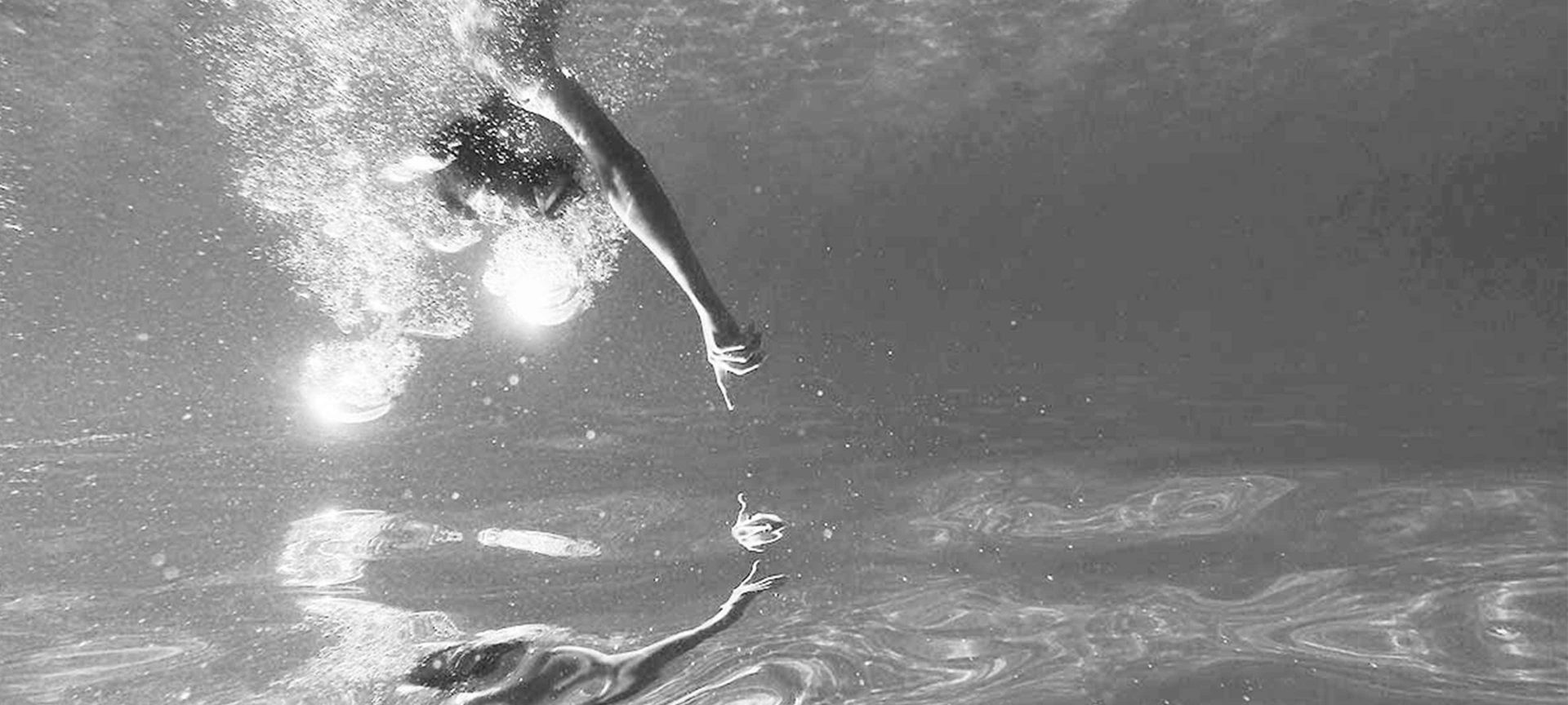 swimmer in a pool swims towards his reflection