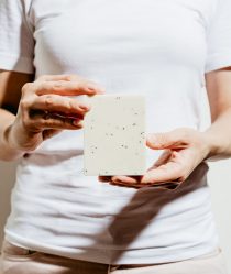 woman holds white bar of soap infront of white t-shirt
