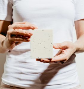 woman holds white bar of soap infront of white t-shirt