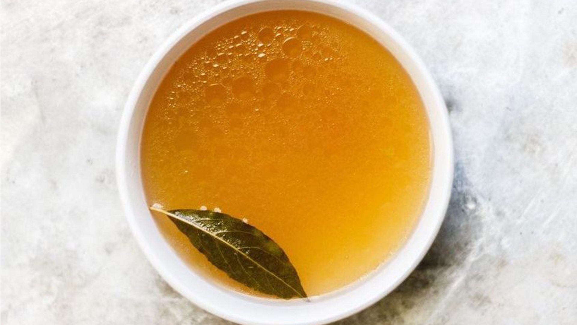 simple cup of broth sitting on a grey marble background