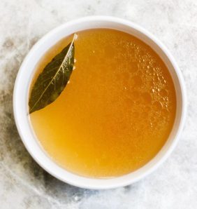 simple cup of broth sitting on a grey marble background