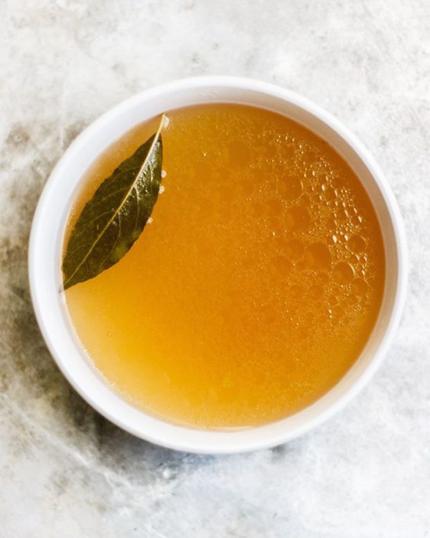 simple cup of broth sitting on a grey marble background