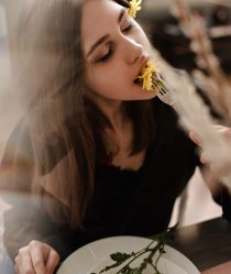 women eating a flower with a look of happiness on her face