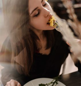 women eating a flower with a look of happiness on her face