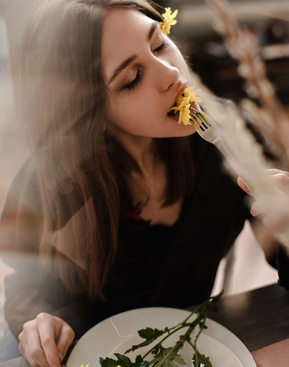 women eating a flower with a look of happiness on her face