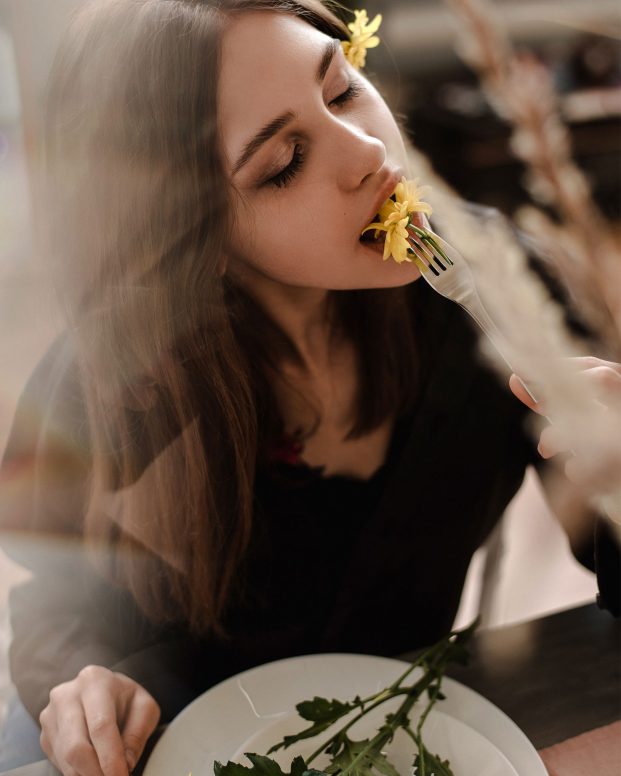 women eating a flower with a look of happiness on her face