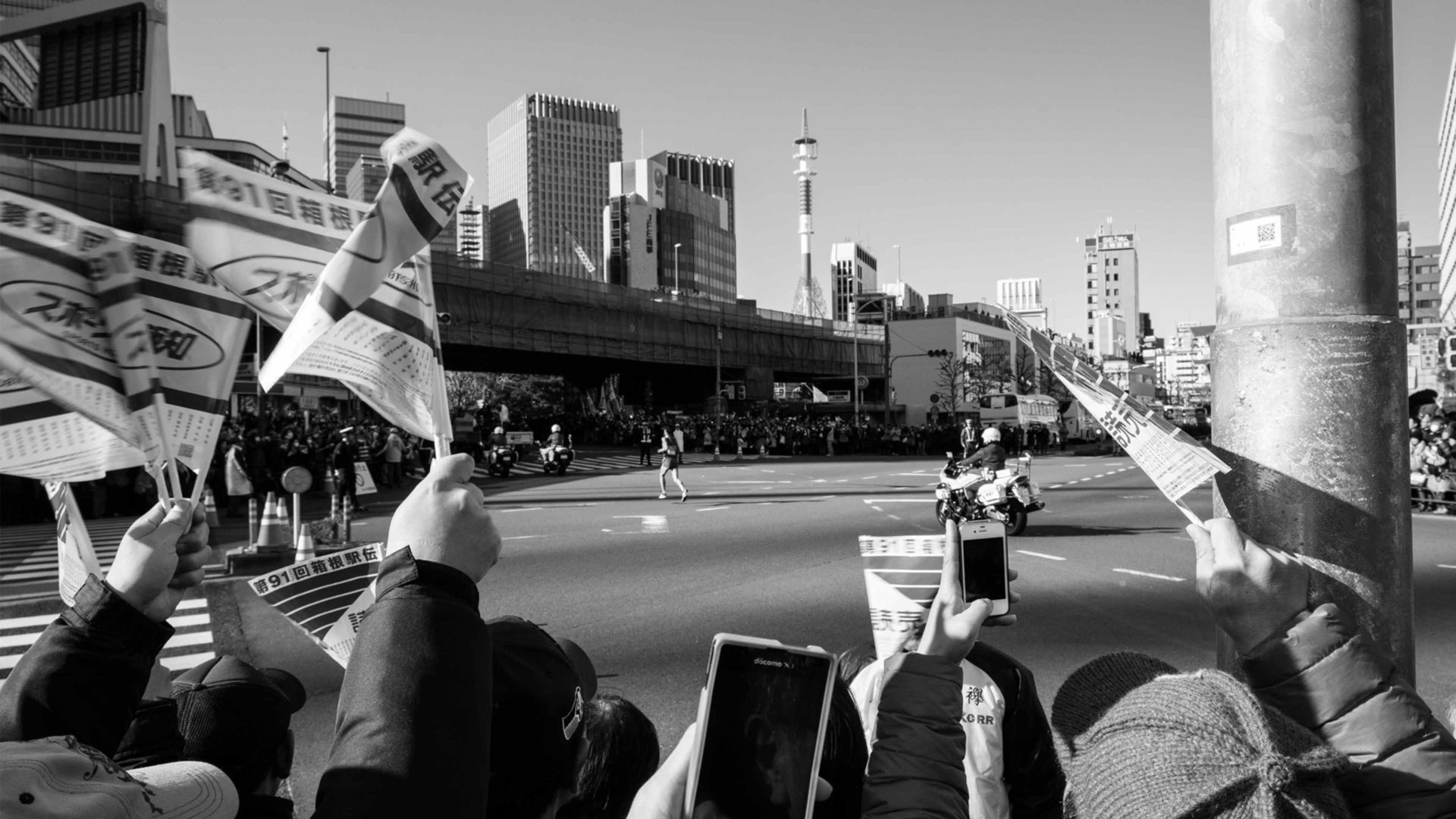 black and white image of flags waving as a long distance runner