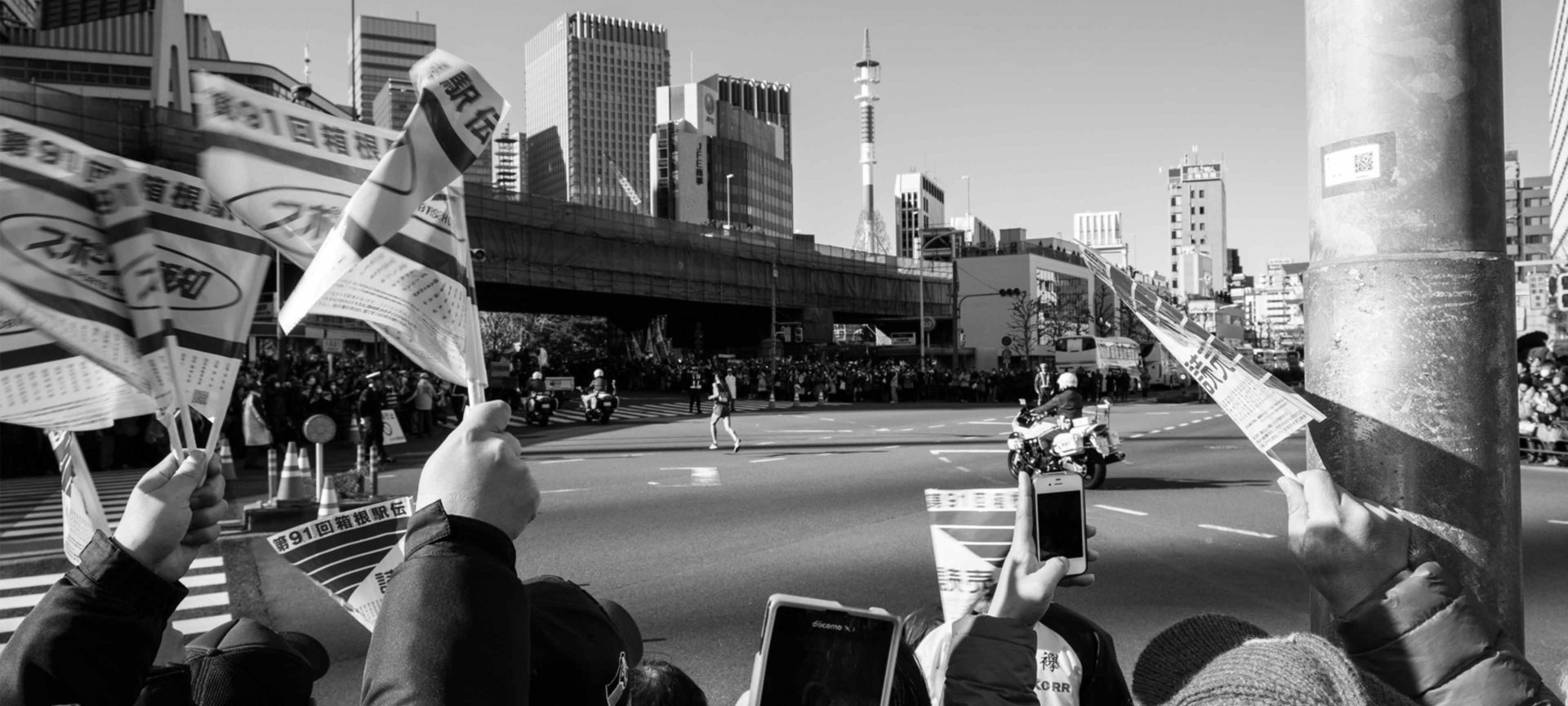 black and white image of flags waving as a long distance runner