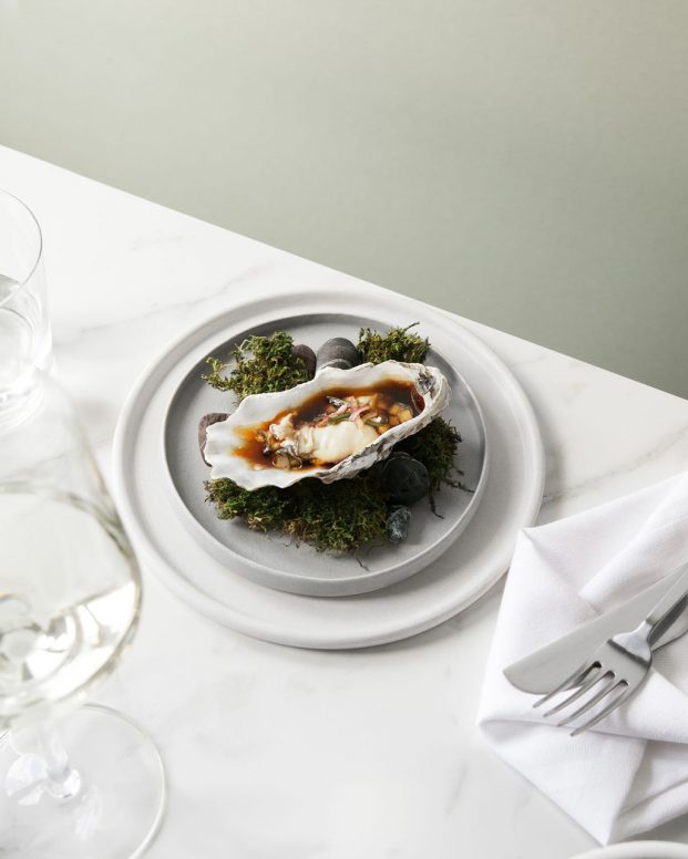 an oyster sitting on a plate on top of grass
