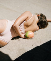 women lying on the sand with a mango