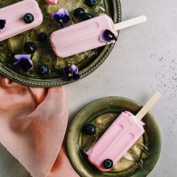 A still life of pink ice cream lollipops in green bowls decorated with flowers