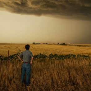 Storm chaser Tim Samaras looks across a field at dark storm clouds