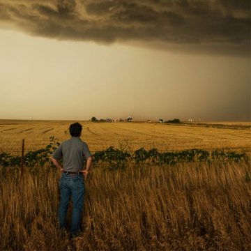 Storm chaser Tim Samaras looks across a field at dark storm clouds