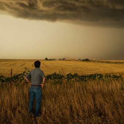 Storm chaser Tim Samaras looks across a field at dark storm clouds