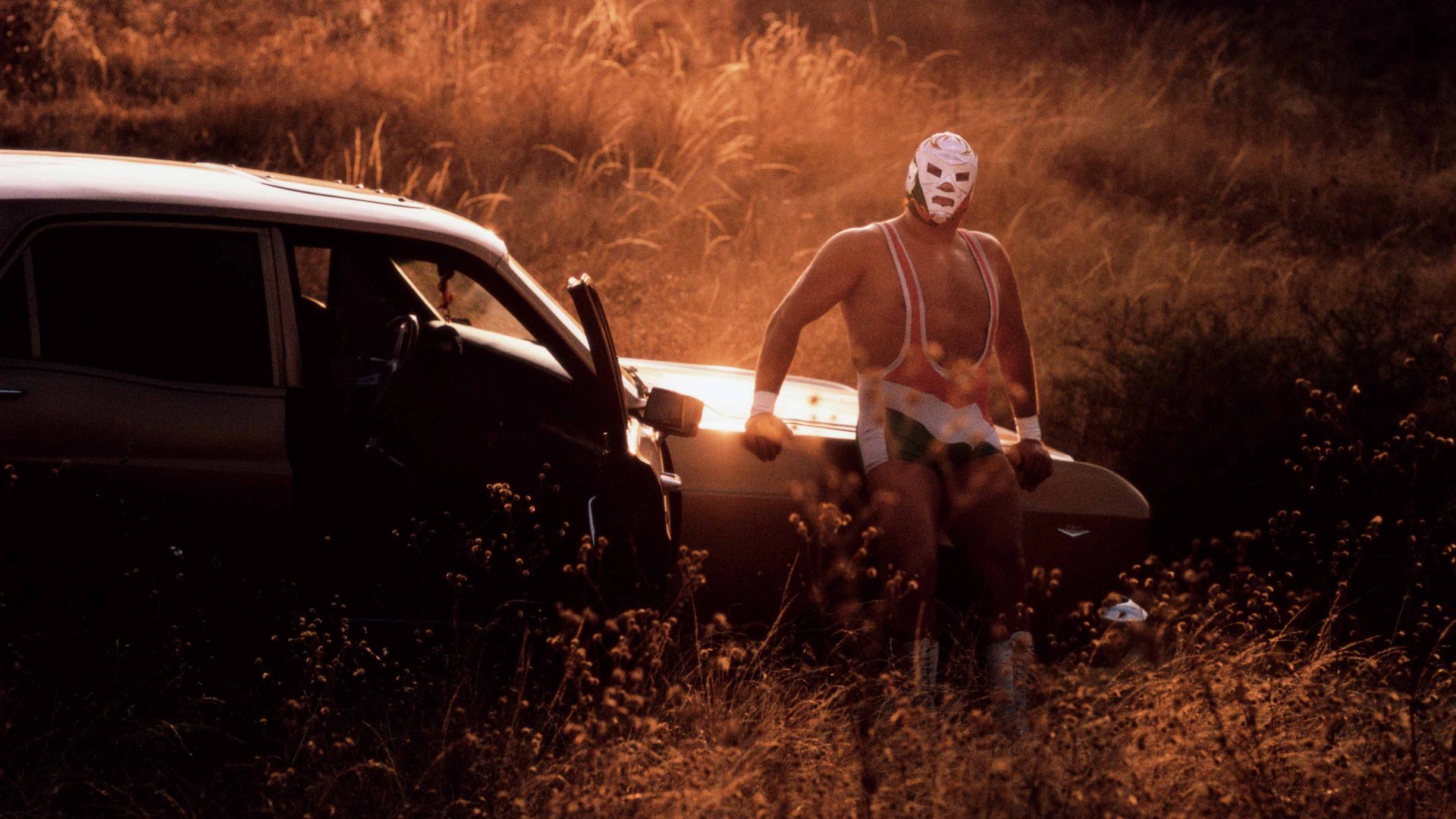 Mexican luchador Dr Wagner Jr poses by his car in front of a sunset
