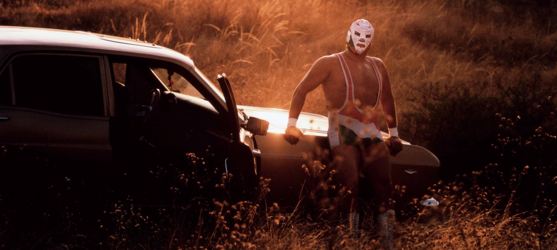 Mexican luchador Dr Wagner Jr poses by his car in front of a sunset