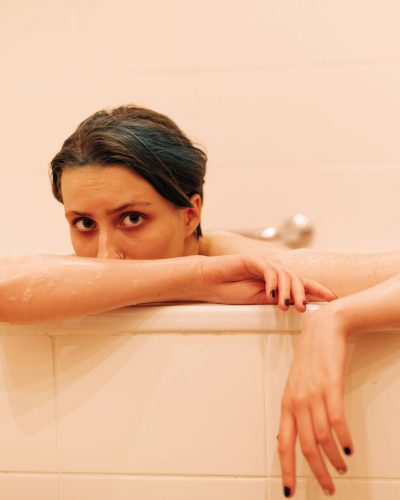 A female model sits in a pink bathtub looking out