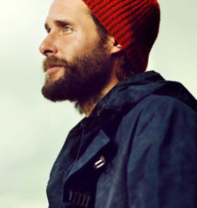 david de rothschild wears a red beanie and outdoor coat infront of a pale green background