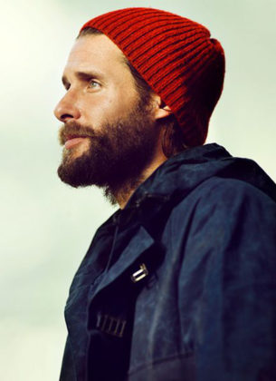david de rothschild wears a red beanie and outdoor coat infront of a pale green background