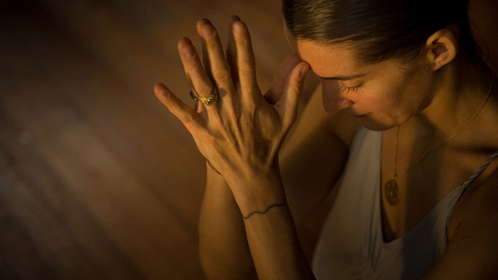 elena brower clasps hands in a yoga pose and holds them to her forehead