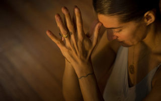 elena brower clasps hands in a yoga pose and holds them to her forehead