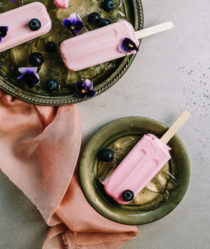 A still life of pink ice cream lollipops in green bowls decorated with flowers