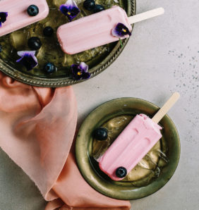 A still life of pink ice cream lollipops in green bowls decorated with flowers