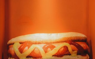 Hot dog with ketchup and mustard on orange background