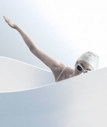woman in a white swimming cap practices swimming motions