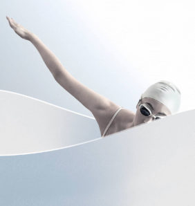woman in a white swimming cap practices swimming motions