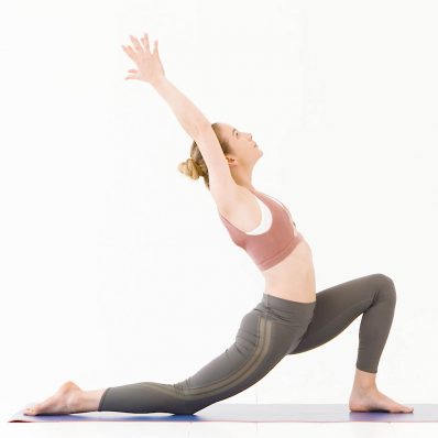 Model wears pink sports bra and green leggings in yoga pose