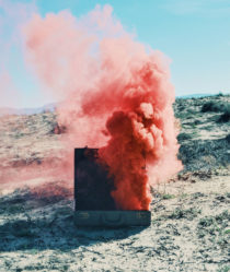 A cloud of pink smoke billows out of a suitcase