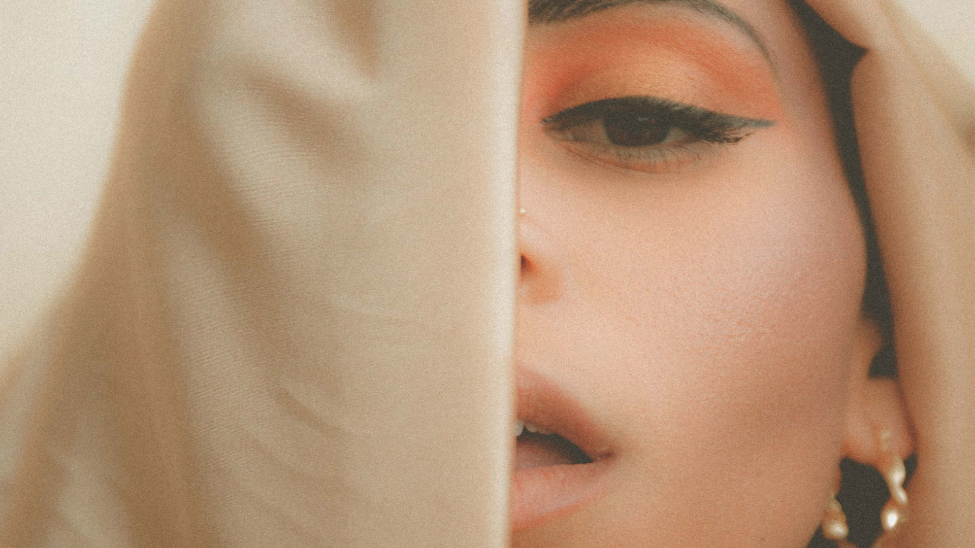 A young woman's face partially obscured by a veil