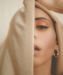 A young woman's face partially obscured by a veil