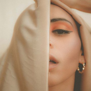 A young woman's face partially obscured by a veil