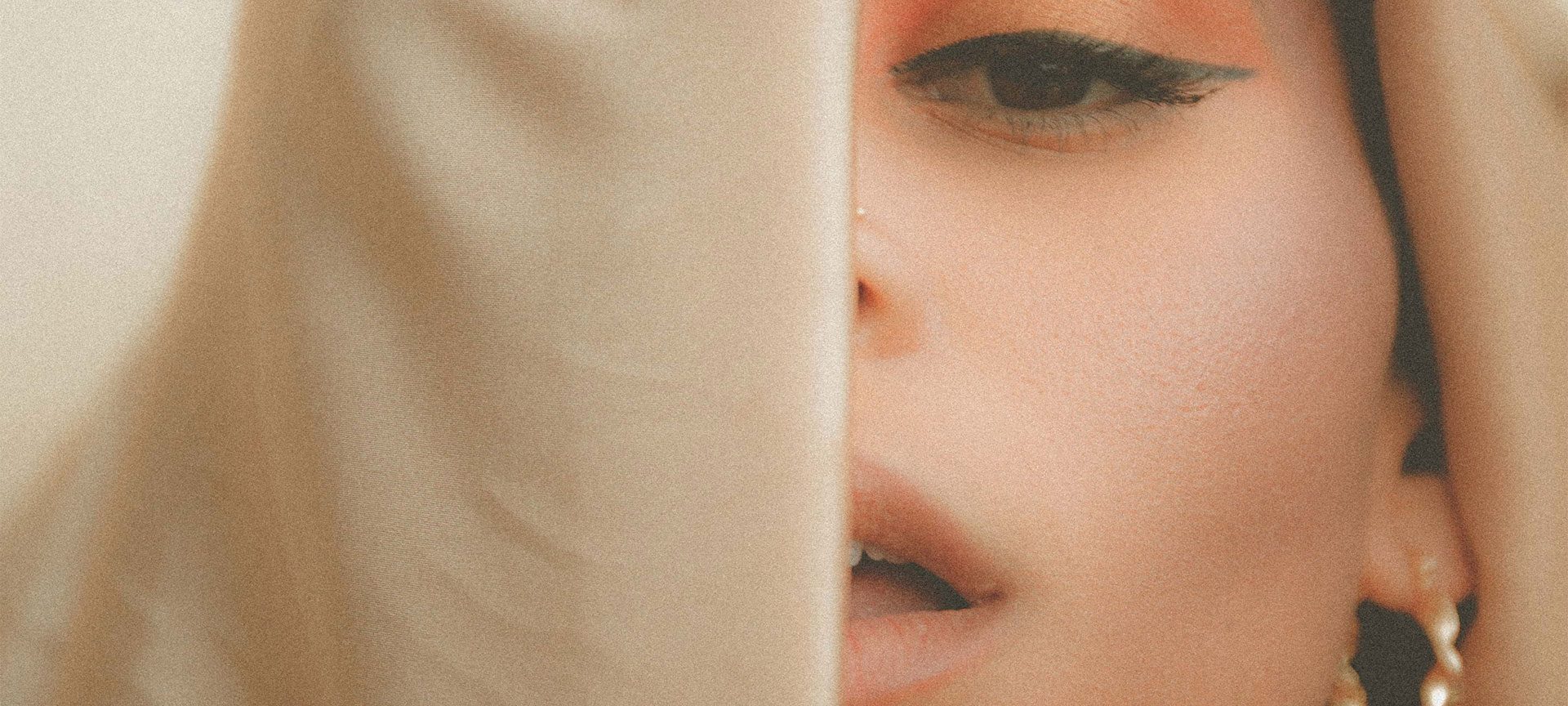A young woman's face partially obscured by a veil